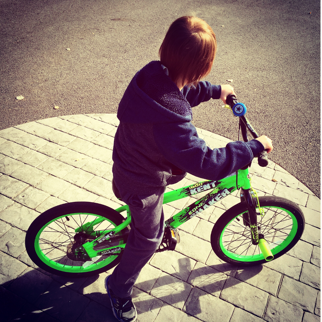 Young boy riding a green bike outdoors