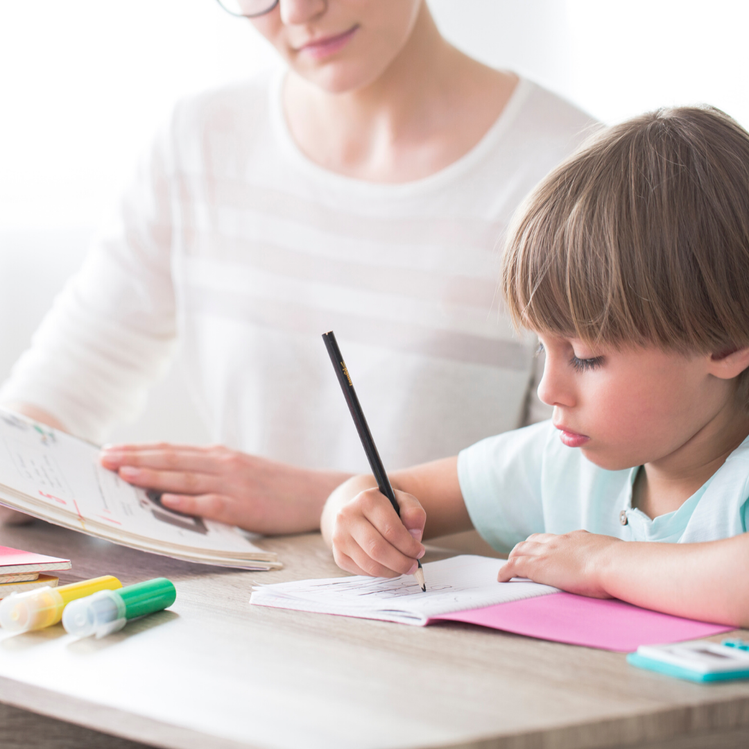 Blog Autism Young boy learning to write sitting at desk with mother