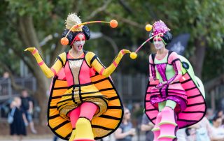 Two people dressed in festiva costumes that represent bugs