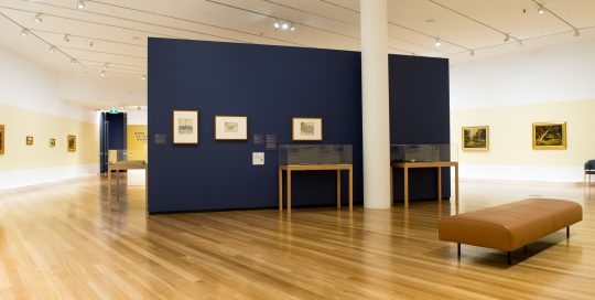 Image shows interior of art gallery with paintings on display