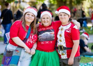 Three people dressed in christmas costumes and santa hats