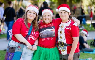 Three people dressed in christmas costumes and santa hats