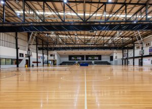 State Basketball Centre showcourt with wooden floor, player bench seating and blue spectator tiered seating