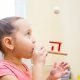 Young girl using a speech therapy device to practice blowing