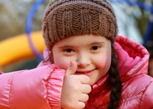 Young girl with disability in a playground giving a thumbs up