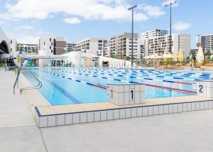 Gunyama Park outdoor 50m swimming pool with lane ropes. City buildings in the background.