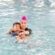Swimming instructor in the water teaching child to swim on back.