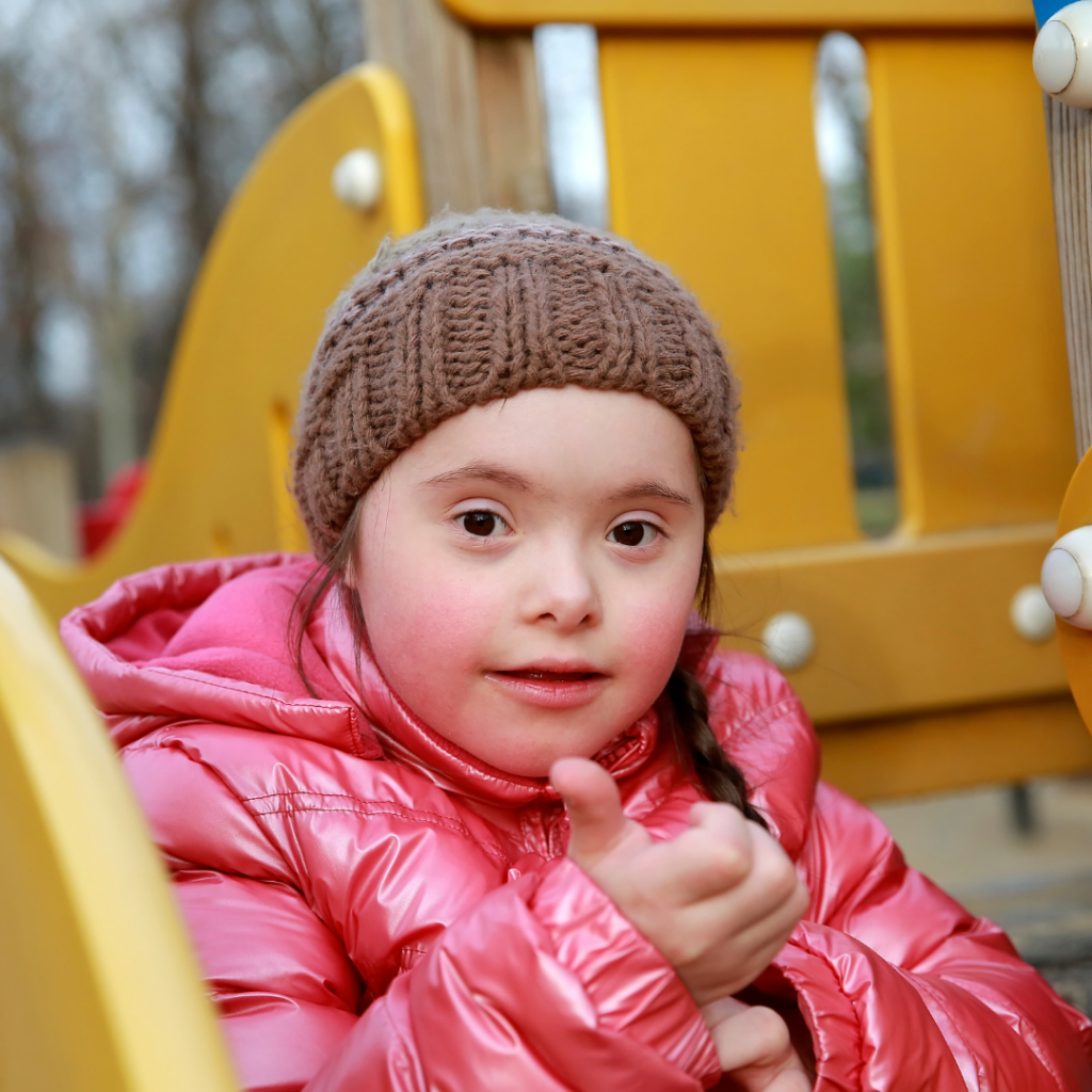 Wellesley Road Playspace SS image Young girl with down syndrome giving thumbs up and playing at outdoor playgound
