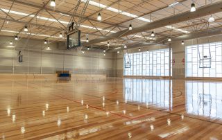 Boroondara Sports Complex indoor basketball stadium with polished wooden floor, lighting, seating and windows