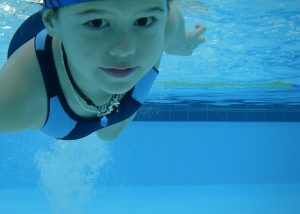 Young child swimming under the water wearing bathers and a swimming cap