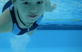 Young child swimming under the water wearing bathers and a swimming cap