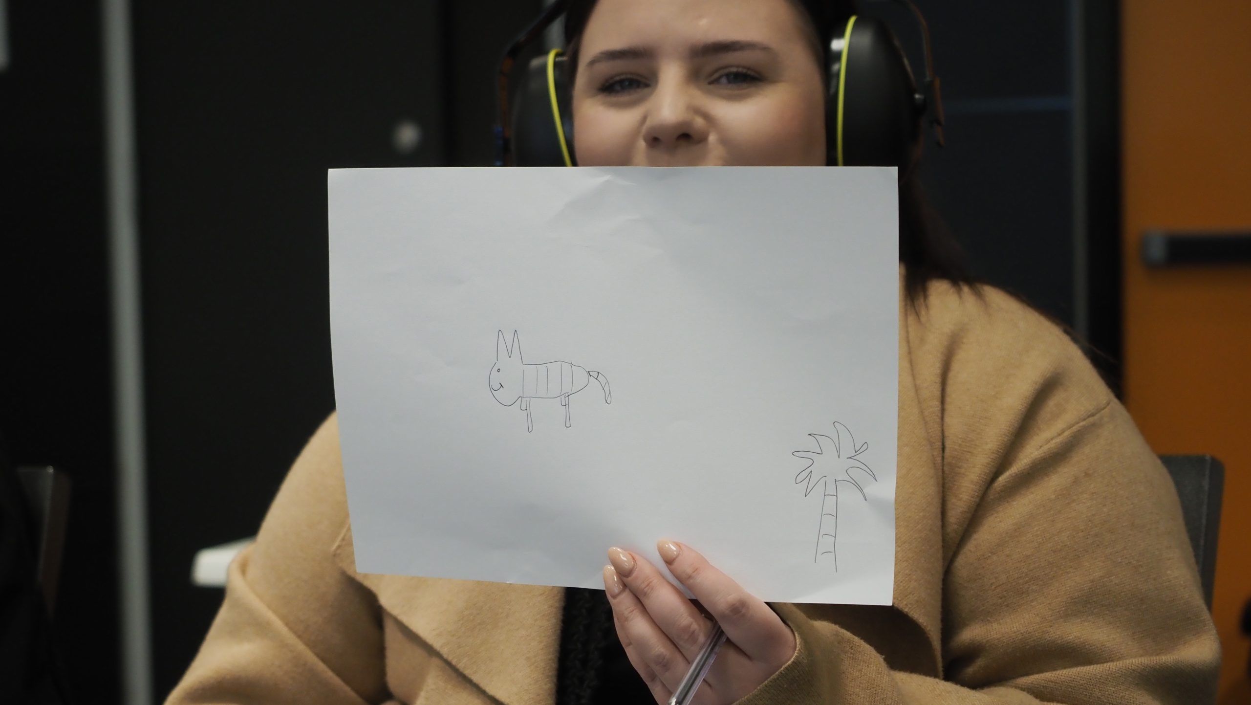 YMCA staff memer holding up white piece of paper with drawing on it