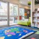 Interior or Broadford Library with bookshelves, books, rug on floor and glass windows and doors leading to outdoor area
