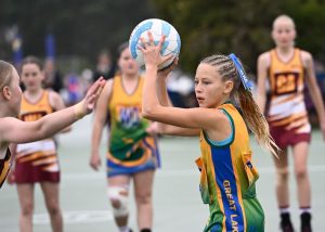 Two girls netball teams playing a game on a court