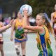 Two girls netball teams playing a game on a court